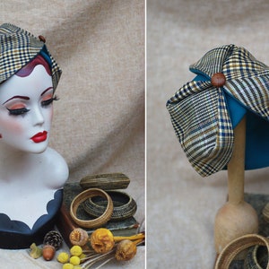 May include: A brown and black plaid hat with a teal lining and a brown button on top. The hat is on a wooden stand.