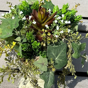 May include: A small, white, decorative planter with a green succulent plant and ivy. The planter has a distressed finish and is filled with a variety of green plants.