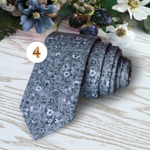 May include: A gray necktie with a white floral pattern. The tie is rolled up and the number 4 is visible in the upper left corner of the image.
