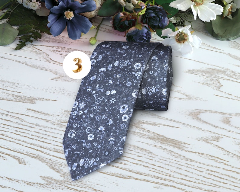 May include: A dark blue necktie with a white floral pattern.