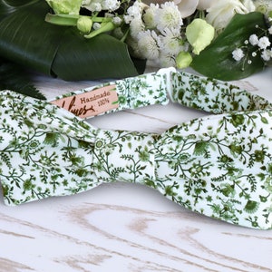 Op de afbeelding: Een witte strik met een groen bloemenpatroon. De strik is handgemaakt en 100% katoen.
