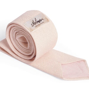 May include: A rolled-up, light pink necktie with a textured weave. The tie is unrolled at the end, revealing a lighter pink lining. A small label with the name "Halmer" and "100% Handmade" is attached to the rolled portion.
