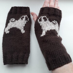 May include: A pair of brown knitted fingerless gloves with a white pug dog design. The gloves are made of a soft, warm yarn and are perfect for keeping your hands warm in the winter.