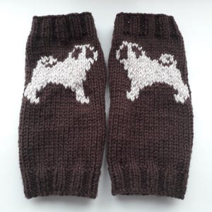 May include: A pair of brown knitted leg warmers with a white pug design.