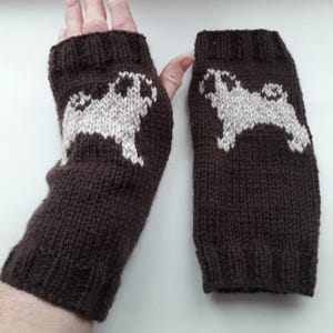 May include: A pair of brown knitted fingerless gloves with a white pug design. The gloves are made of a soft, warm material and are perfect for keeping your hands warm in the winter.