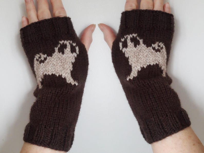 May include: Brown knit fingerless gloves with a white pug design on each glove.