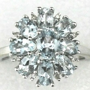 Könnte beinhalten: Ein silberner Ring mit einem Cluster aus hellblauen Aquamarin-Edelsteinen, die in einem floralen Design gefasst sind.