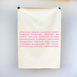 Può includere: Un asciugamano da cucina bianco con testo rosa che elenca diverse parole e frasi tedesche, tra cui "elbtunnel", "krüsch", "neuwerk", "veddel", "barkasse", "billwerder", "elbbrücke", "hh", "dock11", "schnack", "dafürnich", "bunker", "schweinesand", "freihafen", "waltershof", "kaispeicher", "tiefstack", "tüdel", "altona", "schlepper", "lassdasnach", "040", "lütten", "mittenmang", "plietsch" e "schnoopkram".