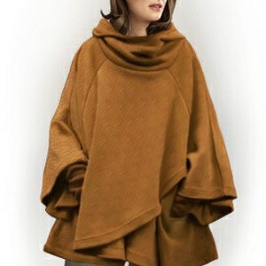 May include: A solid tobacco-colored poncho featuring a wide, draped cowl neckline, loose-fitting sleeves, and a layered, asymmetrical hemline. The garment is constructed from a textured fabric and provides a relaxed, flowing silhouette.