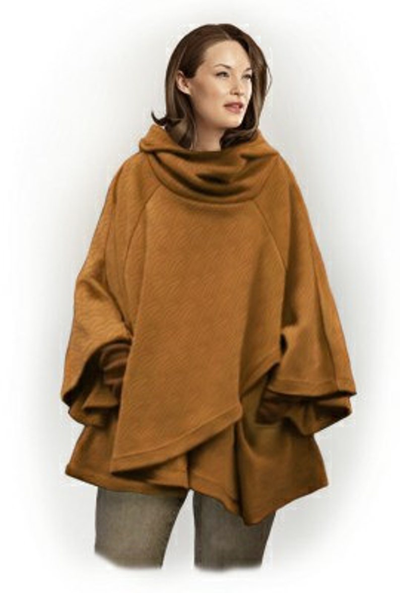 May include: A solid tobacco-colored poncho featuring a wide, draped cowl neckline, loose-fitting sleeves, and a layered, asymmetrical hemline. The garment is constructed from a textured fabric and provides a relaxed, flowing silhouette.