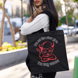 Puede incluir: Bolso tote negro con un gráfico de diablo rojo y el texto "I'm not like other girls, I'm way worse!" El bolso tiene dos asas y está hecho de un material duradero. El gráfico presenta un diablo guiñando un ojo.