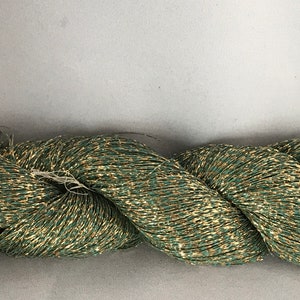 May include: A skein of green and gold metallic yarn. The yarn is made of a fine, shimmering thread that is perfect for creating delicate and elegant projects.