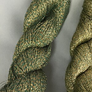 May include: Two spools of green and gold metallic thread. The thread is twisted and has a shiny finish.
