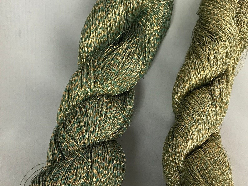 May include: Two spools of green and gold metallic thread. The thread is twisted and has a shiny finish.