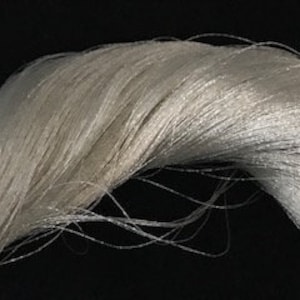 May include: A bundle of white, silky, and delicate threads. The threads are tightly woven together and have a soft, lustrous sheen.