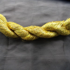 May include: A spool of gold metallic yarn with a shimmery finish.