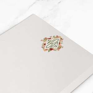 Puede incluir: Bloc de notas rectangular blanco con un diseño floral de monograma en la esquina superior derecha. El bloc de notas mide 10,8 x 15,9 cm. Dos clips plateados están en el fondo.