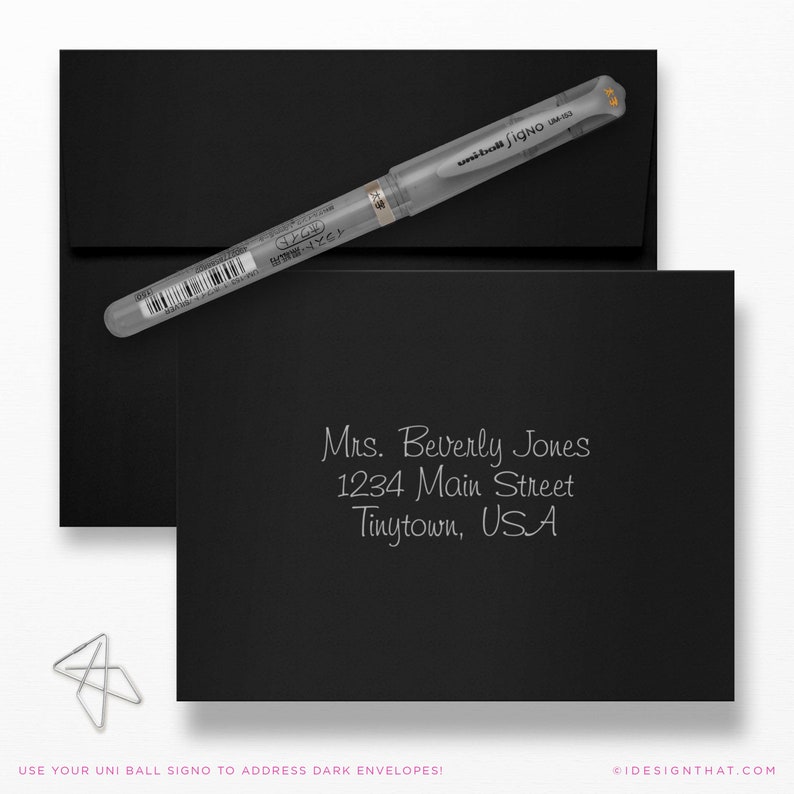 May include: A black stationery set featuring a silver pen and a silver paper clip. The set includes a black envelope and a black card with the address "Mrs. Beverly Jones, 1234 Main Street, Tinytown, USA" written in silver ink. The text "USE YOUR UNI BALL SIGNO TO ADDRESS DARK ENVELOPES!" is also visible.