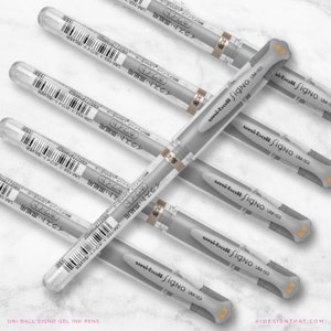 May include: A selection of silver Uni-ball Signo UM-153 gel ink pens. Each pen is housed in a clear plastic tube, with the pen's body in a light grey colour. The text "uni-ball Signo UM-153" is printed on the pen's body.