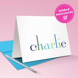 A folded rainbow note card displayed upright shows the premium cardstock of this kids stationary set of colorful thank you cards.