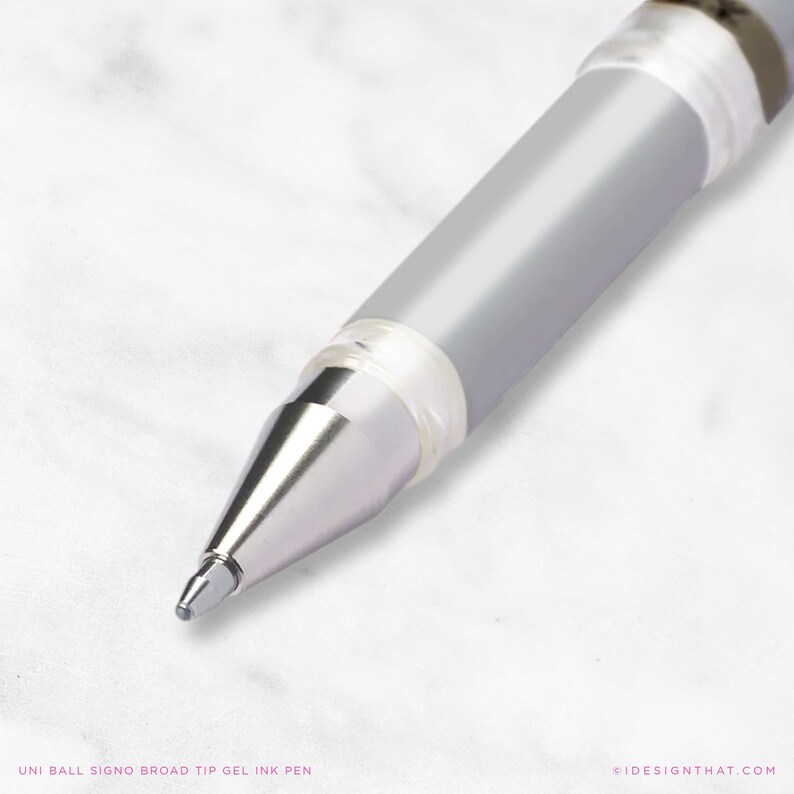 May include: A close-up shot of a silver and clear Uni-ball Signo Broad Tip gel ink pen. The pen features a silver barrel and a transparent grip. The pen's tip is in focus, with the text "UNI BALL SIGNO BROAD TIP GEL INK PEN" at the bottom.