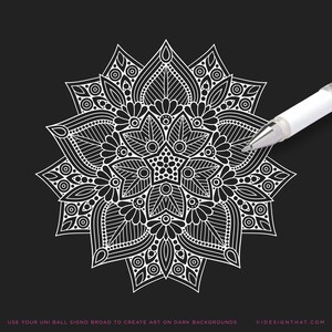 May include: A white pen illustrating a complex mandala design on a black backdrop. The mandala showcases elaborate floral and geometric patterns. The image includes the text "USE YOUR UNI BALL SIGNO BROAD TO CREATE ART ON DARK BACKGROUNDS".