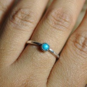 Puede incluir: Un anillo de plata con una pequeña piedra turquesa engastada en el centro.