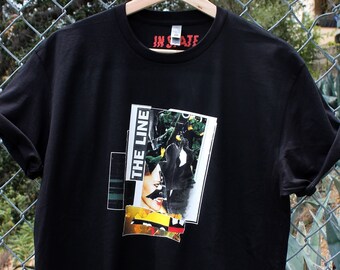 May include: Black t-shirt with a graphic print of a woman's face with the text "The Line" on the left side of the graphic. The text "In State" is printed in red on the neck of the shirt.