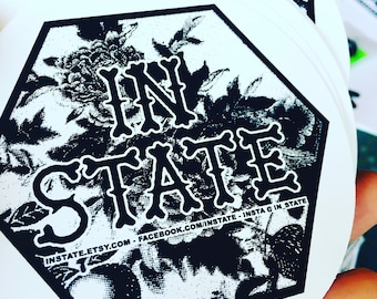 May include: Black and white sticker with a hexagonal shape and a floral design. The sticker says "IN STATE" in bold, stylized lettering. The text "INSTATE.ETSY.COM - FACEBOOK.COM/INSTATE - INSTA @ IN_STATE" is printed at the bottom of the sticker.