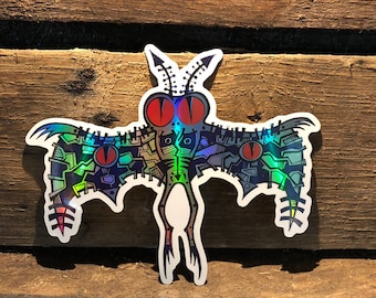 May include: A holographic sticker of a colorful, detailed, insect-like creature with large red eyes and wings. The creature has a green body and is set against a wood background.