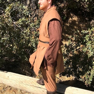 May include: A brown robe with a brown belt and brown trousers. The robe has a brown collar and a brown sleeve. The person is wearing brown boots.