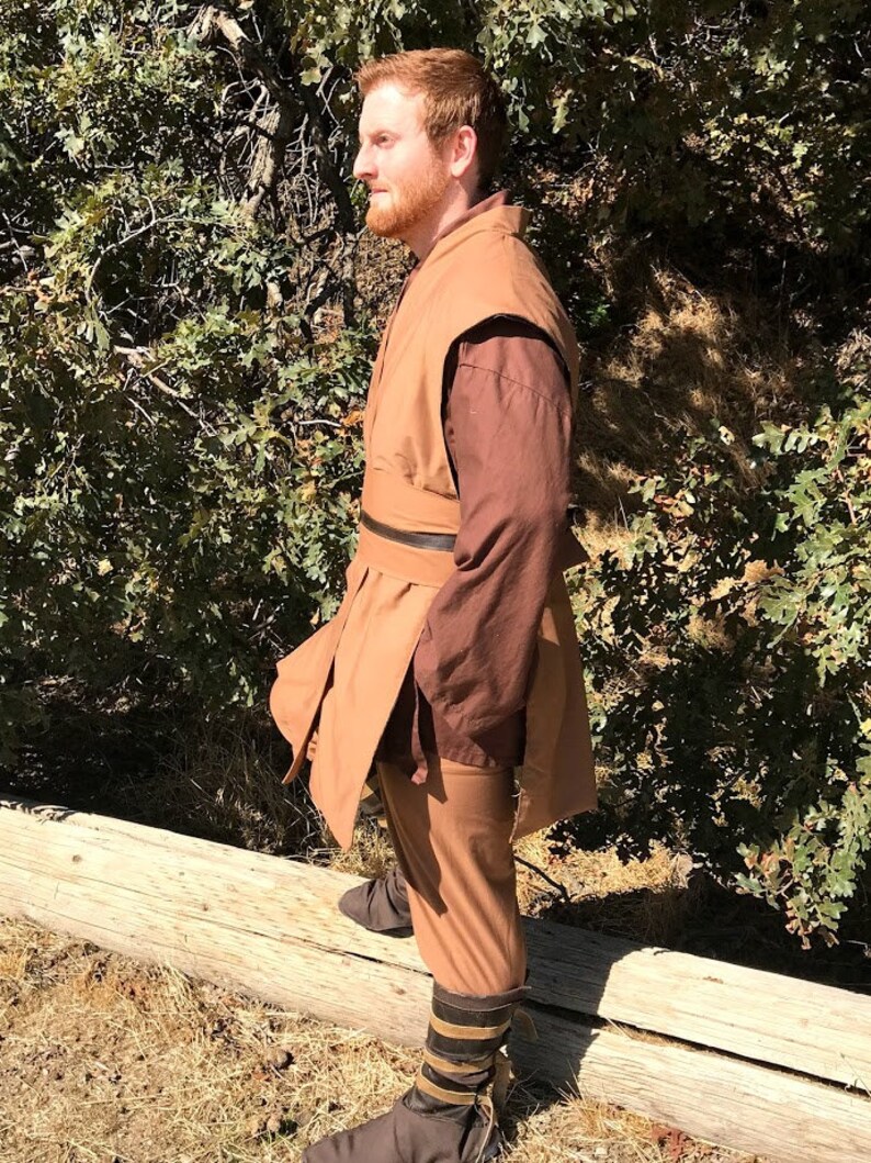 May include: A brown robe with a brown belt and brown trousers. The robe has a brown collar and a brown sleeve. The person is wearing brown boots.