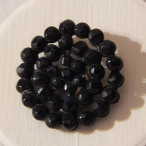 May include: A black button made of faceted glass beads arranged in a spiral pattern.