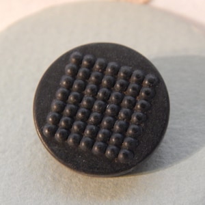 May include: A black button with a raised pattern of small circles.