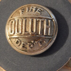 May include: Silver button with the words "FIRE DULUTH DEPT" embossed on it.