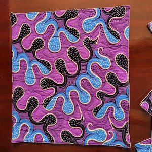 May include: Purple and blue quilted placemat with a geometric pattern of swirls and dots.