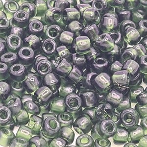 Pode incluir: Uma grande quantidade de contas de sementes de vidro verde escuro. As contas s&atilde;o opacas e t&ecirc;m um acabamento ligeiramente iridescente.