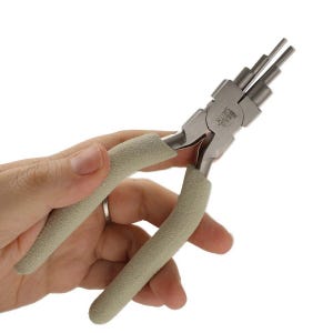May include: A pair of silver-colored jewelry pliers with tan cushioned handles. The pliers have multiple rounded tips of varying sizes. The brand name "SMITH" is visible on the pliers. The pliers are held in a hand.