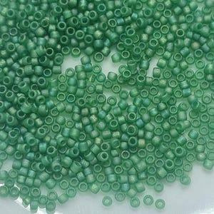 May include: A close-up view of a large quantity of small, round, green glass beads. The beads have a slightly iridescent finish.