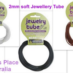 Op de afbeelding: Drie spoelen met 2 mm zachte sieradenbuis, een witte, een zwarte en een bruine. De spoelen zijn gelabeld met "jewelry tube" en "Beadsmith".