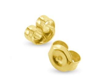May include: Two gold-coloured earring backs. The backs are shaped like a small, open circle with a curved, pointed tab on each side.