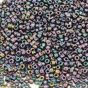 May include: A large quantity of small, iridescent, round beads in shades of purple, green, and brown. The beads have a metallic finish and are perfect for jewelry making.