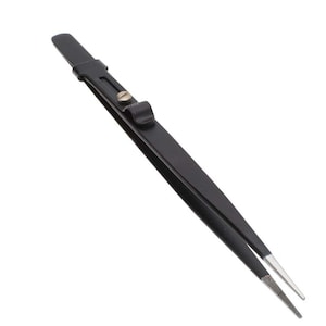 May include: Black tweezers with a silver tip and a black handle. The tweezers have a small metal clasp and a screw. The tips of the tweezers are finely serrated.