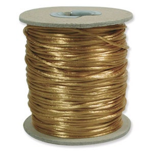 May include: A spool of gold satin cord. The cord is wound tightly around a cardboard spool.
