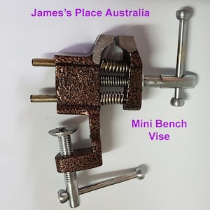 May include: A small, brown metal bench vise with two adjustable handles. The vise is labeled "Mini Bench Vise".