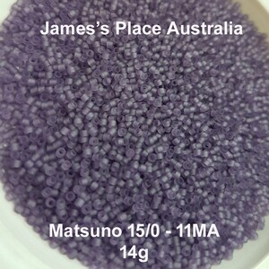 May include: A close-up image of a large quantity of small, translucent purple beads. The beads are in a white bowl and the text "Matsuno 15/0 - 11MA 14g" is visible at the bottom of the image.