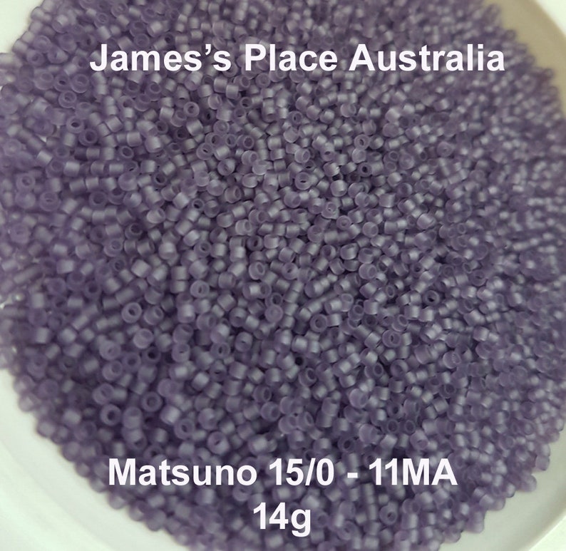 May include: A close-up image of a large quantity of small, translucent purple beads. The beads are in a white bowl and the text "Matsuno 15/0 - 11MA 14g" is visible at the bottom of the image.