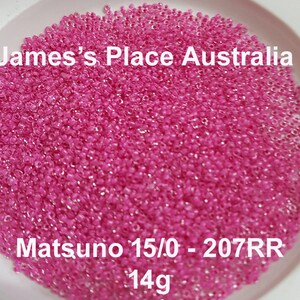 May include: A close-up of a large quantity of pink seed beads. The beads are in a white bowl and the text "James's Place Australia" and "Matsuno 15/0 - 207RR 14g" is visible.