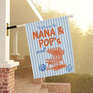 May include: A rectangular flag with blue and white vertical stripes. The flag has the words "Welcome to NANA & POP's pool" in orange and blue. An illustration of a beach chair, a beach ball, and sandals are also on the flag.