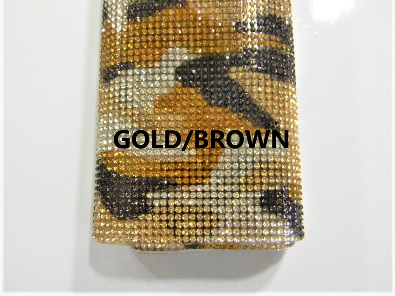 May include: A close-up of a gold and brown fabric with a rhinestone pattern. The fabric has a tiger print design. The text "GOLD/BROWN" is visible on the fabric.